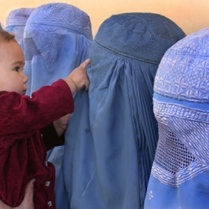A group of women club in burqas waiting in the Dashti Barchi Clinic in Kabul to have their children vaccinated, Sep 28, 2004. Photo by Farzana Wahidy